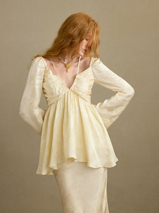 Model wearing the Opaline Jacquard Flare Blouse, a floral jacquard off-shoulder top with adjustable straps, flared hem and long bell sleeves for an elegant dressed-up look – SINCETHEN. 